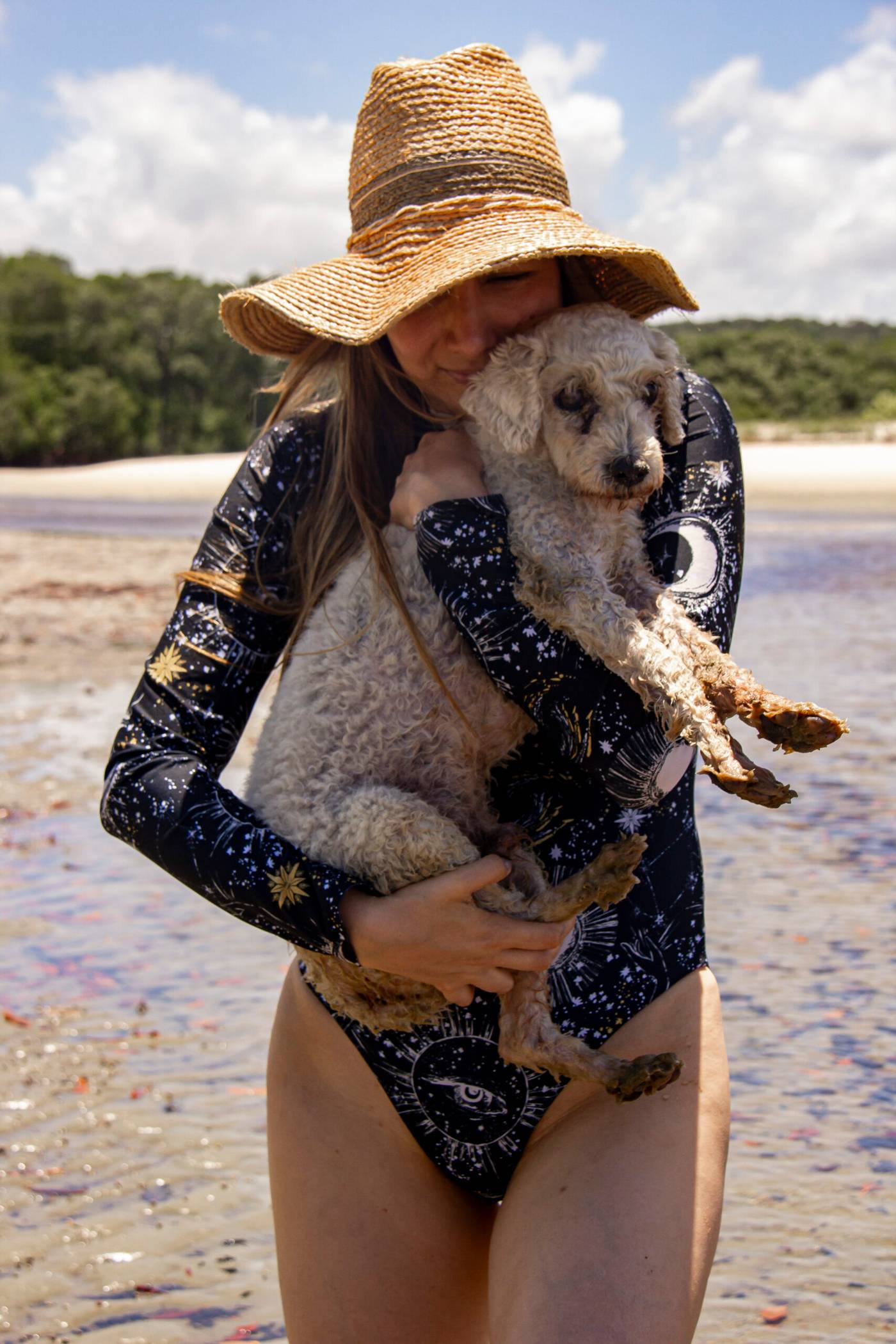 Mujer con sombrero de paja abrazando al perro José Bob en la playa