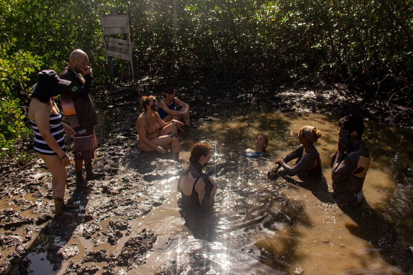 Grupo tomando un baño de arcilla en el manglar de la Ilha do Amor