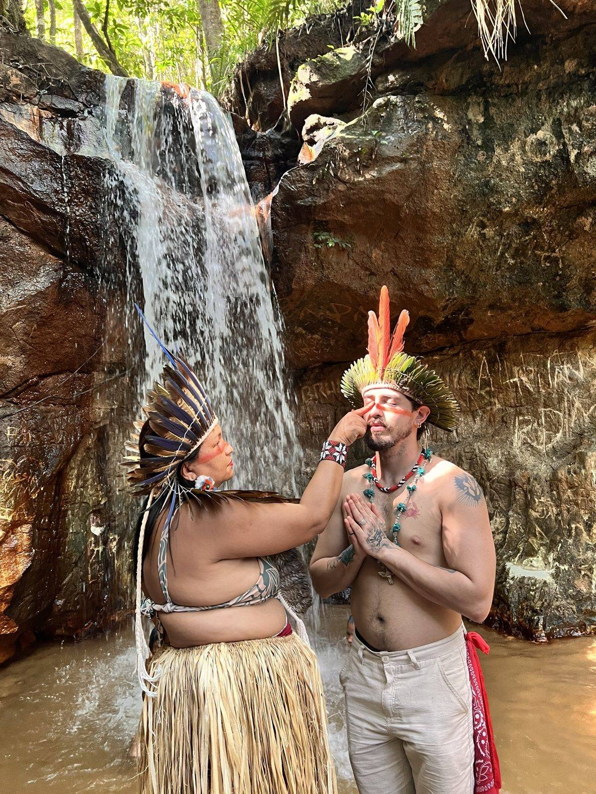 La Majé pintando con urucum el rostro de un participante frente a la cascada